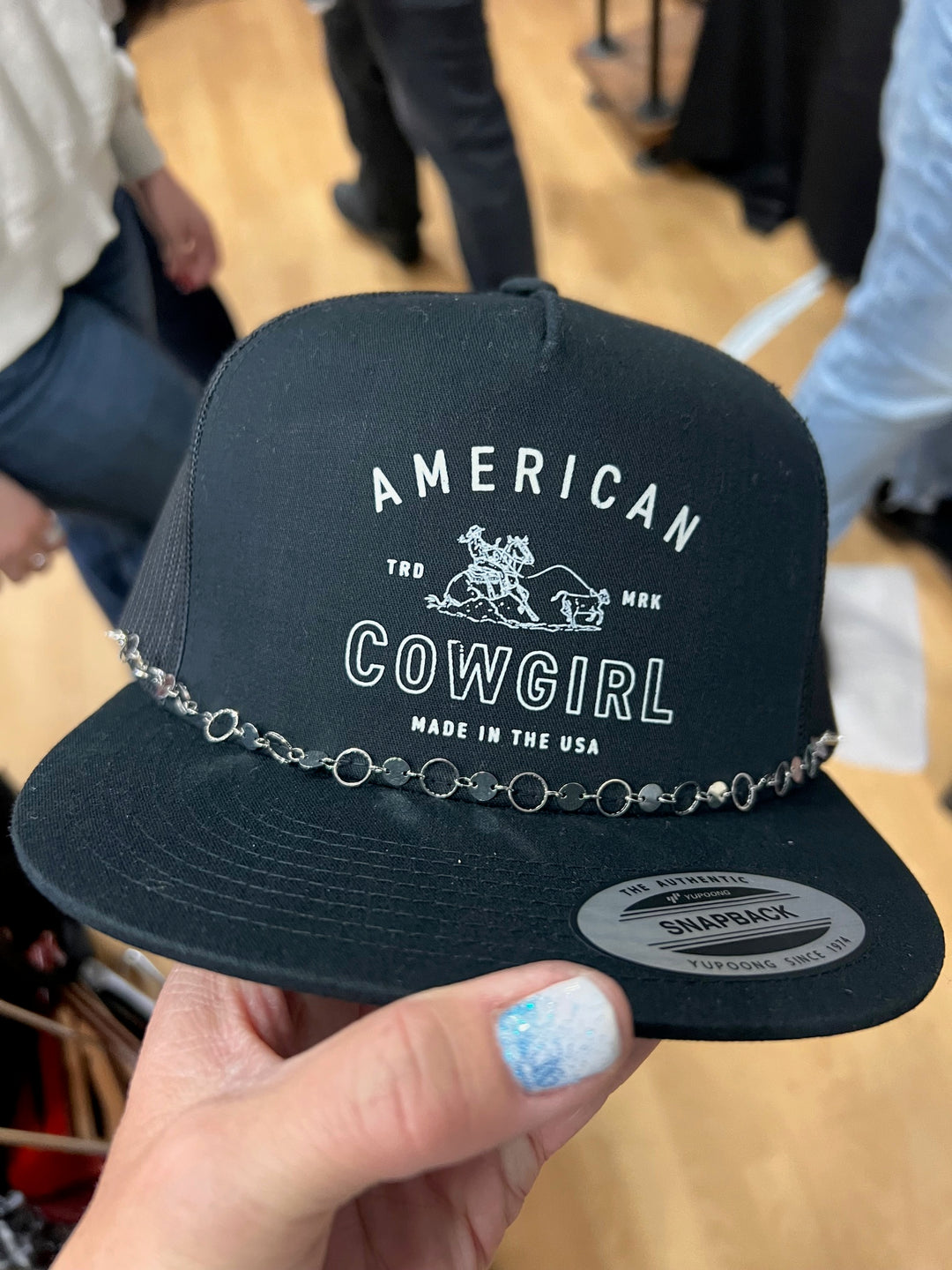 A black ballcap with 'AMERICAN COWGIRL' and 'MADE IN THE USA' text embroidered on the front.
