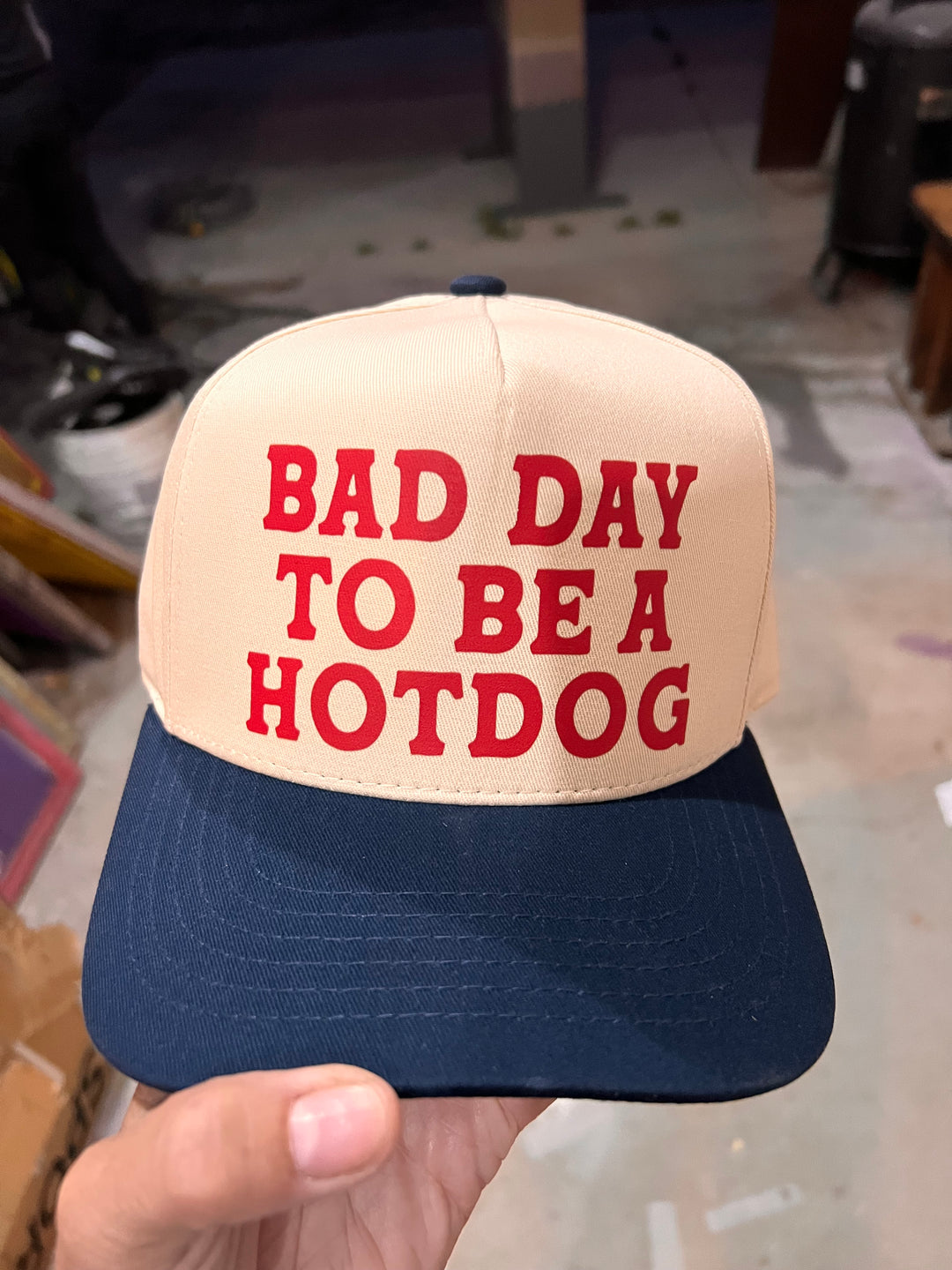 Cap with 'Bad Day to be a Hotdog' text held by a person