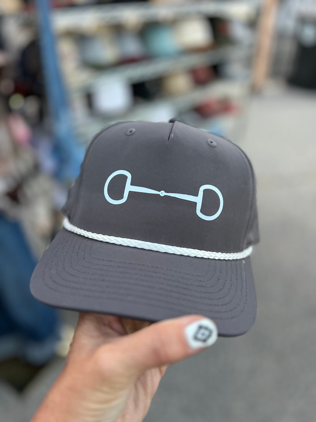 Gray cap with a bit held by a hand in an indoor setting