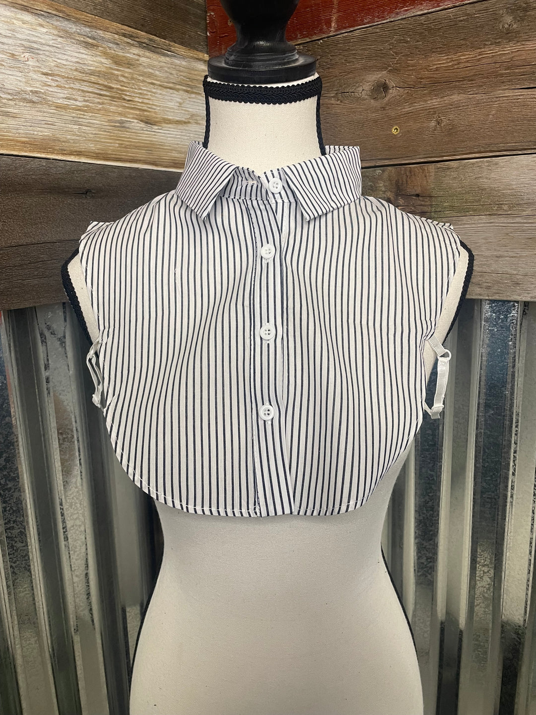 Mannequin wearing a black and white striped dress with a wooden floor background