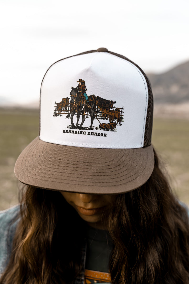 A ballcap with a graphic design of a cowgirl on a horse and text &
