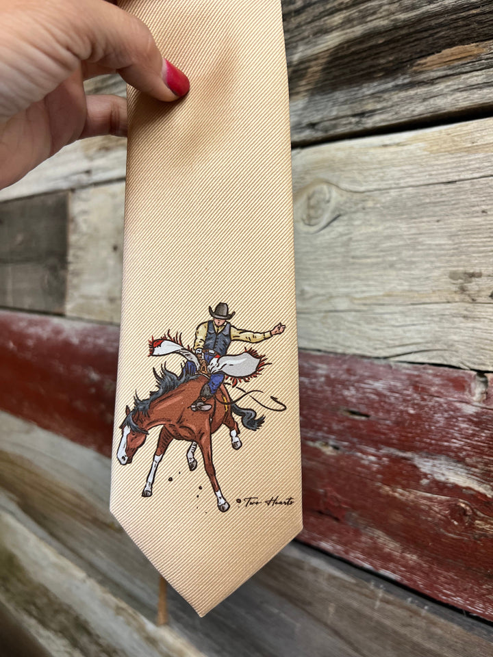 Beige necktie with a cowboy riding a horse design held against a wooden background