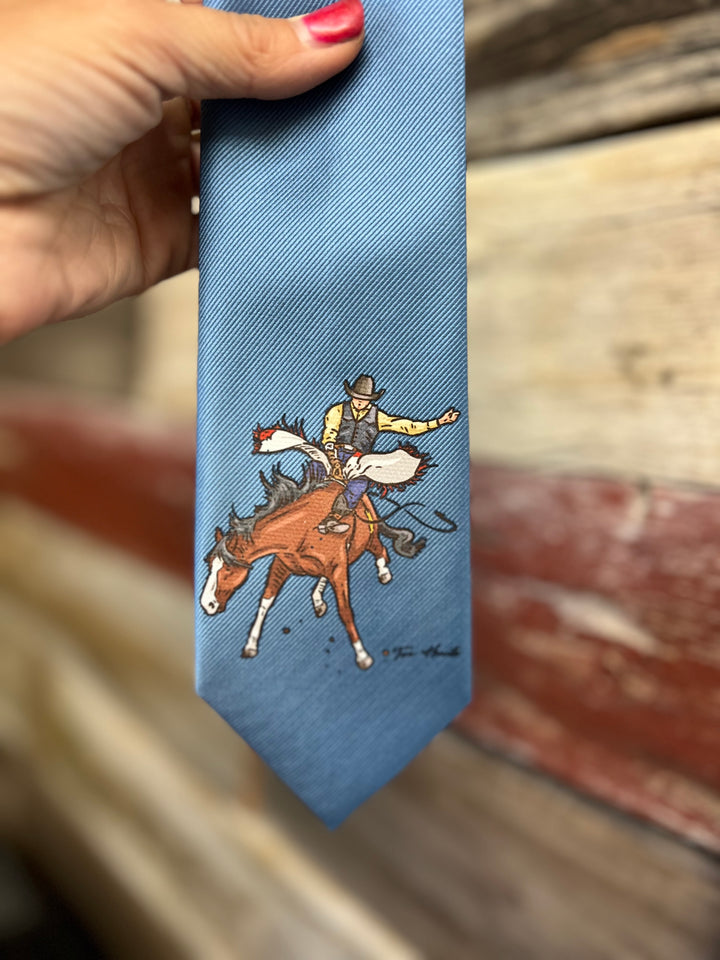 Blue tie with a cowboy and horse design held by a hand on a wooden surface