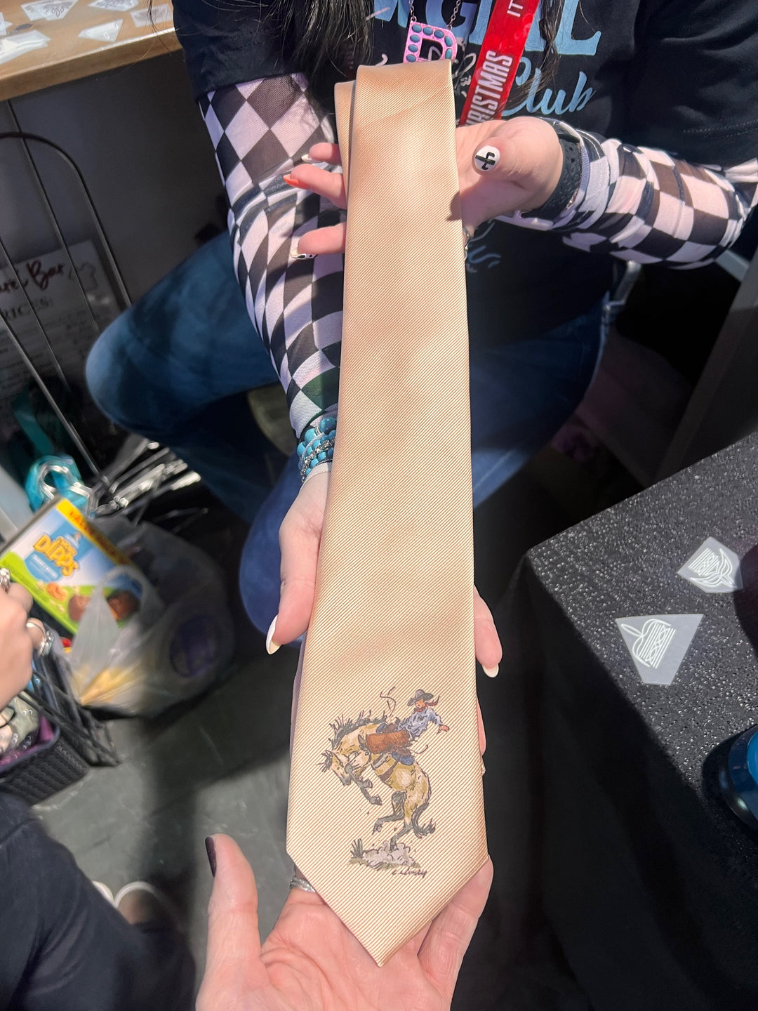 Person holding a long, narrow beige object with a colorful design on it.