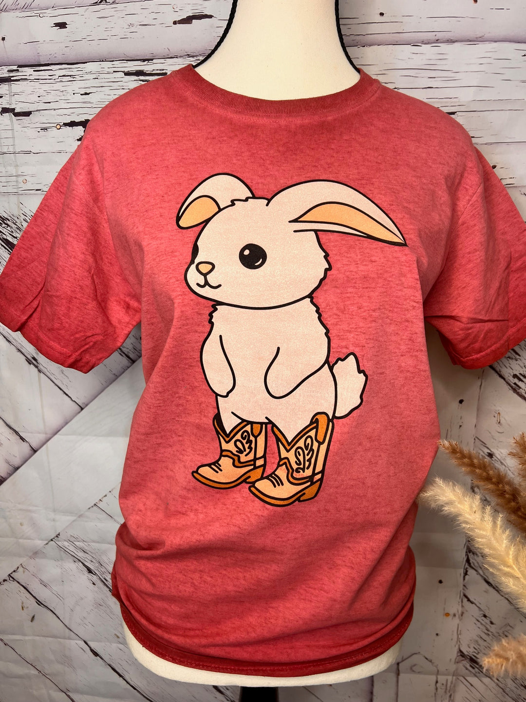 A pink acid-wash t-shirt with a graphic of a cartoon bunny wearing cowboy boots.