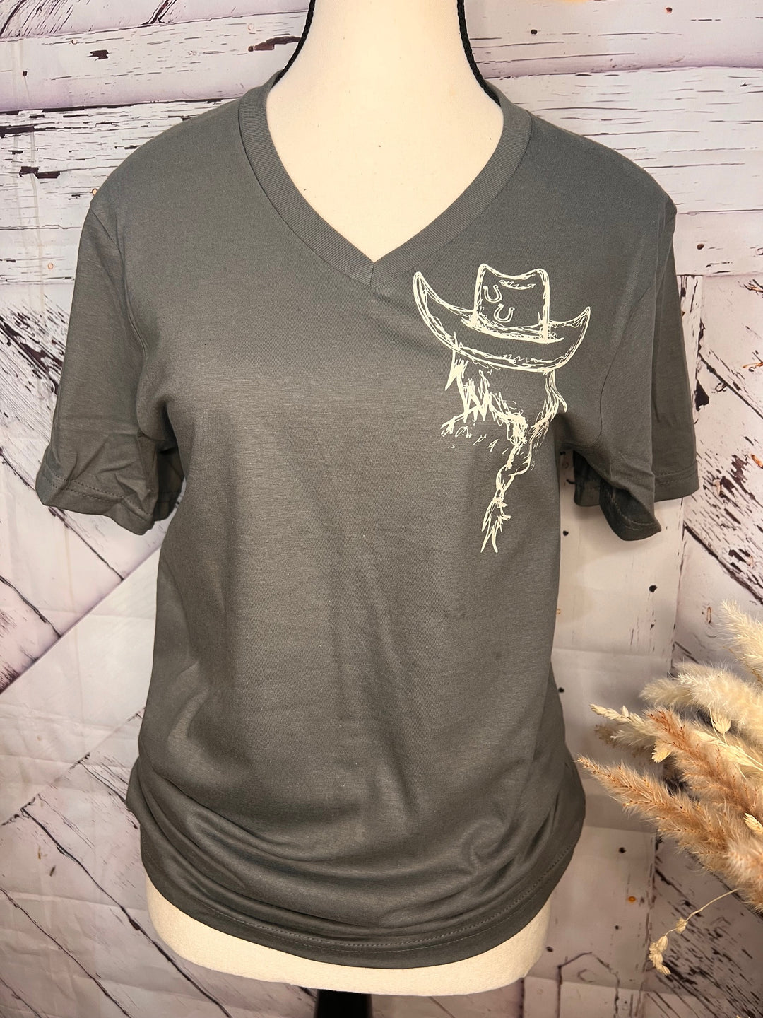 A gray v-neck graphic tee with a white line-drawn image of a cowgirl on the front.