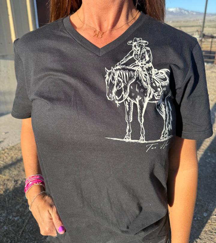 A person wearing a black V-neck tee with a graphic of a cowgirl reaching up to pat a horse&