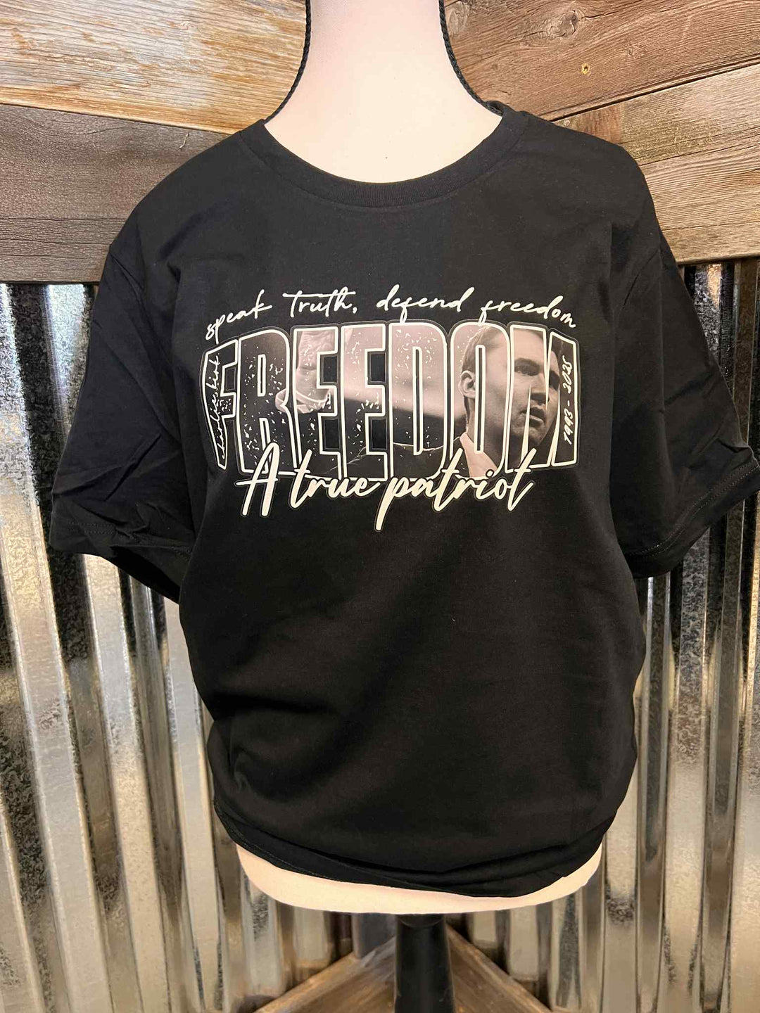 Black t-shirt with graphic design and text on a wooden background