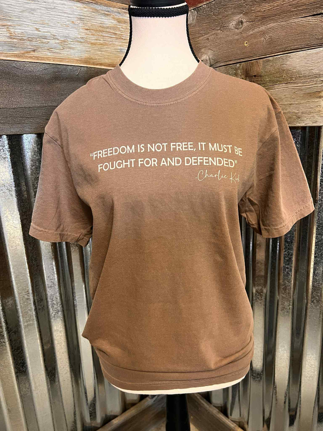 Brown t-shirt with text on a mannequin against a wooden background
