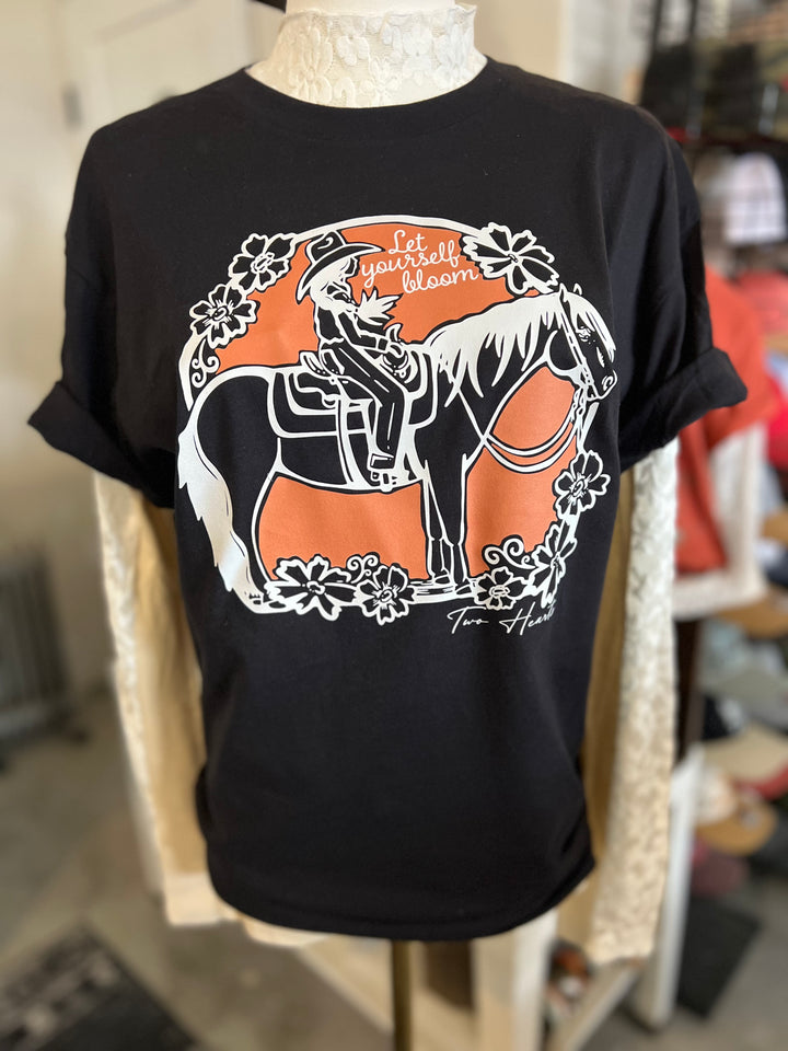 Black t-shirt with a graphic of a person on a horse and floral elements, displayed on a mannequin.