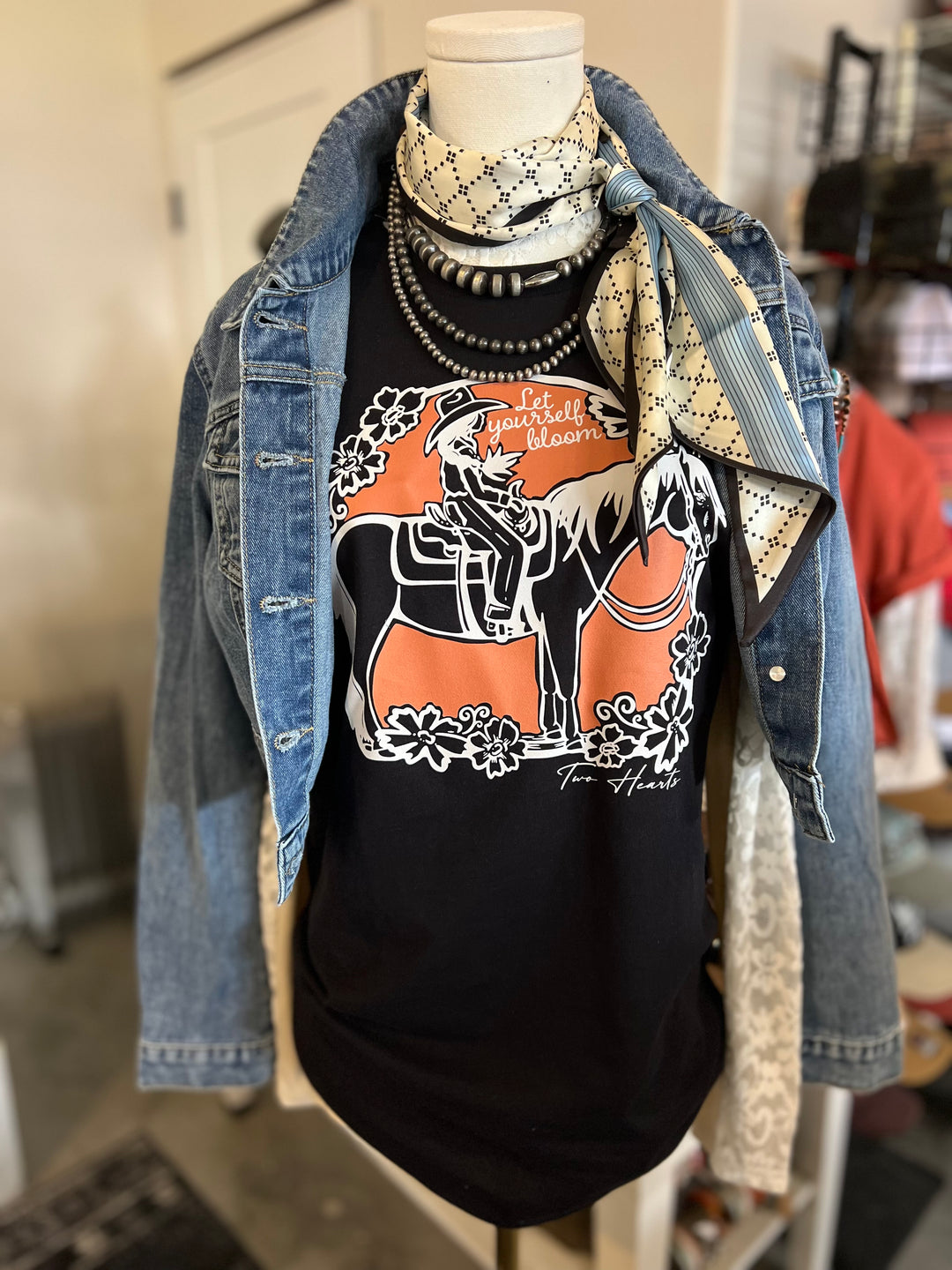 Mannequin wearing a black graphic t-shirt with a horse design, denim jacket, and patterned scarf in a store setting.