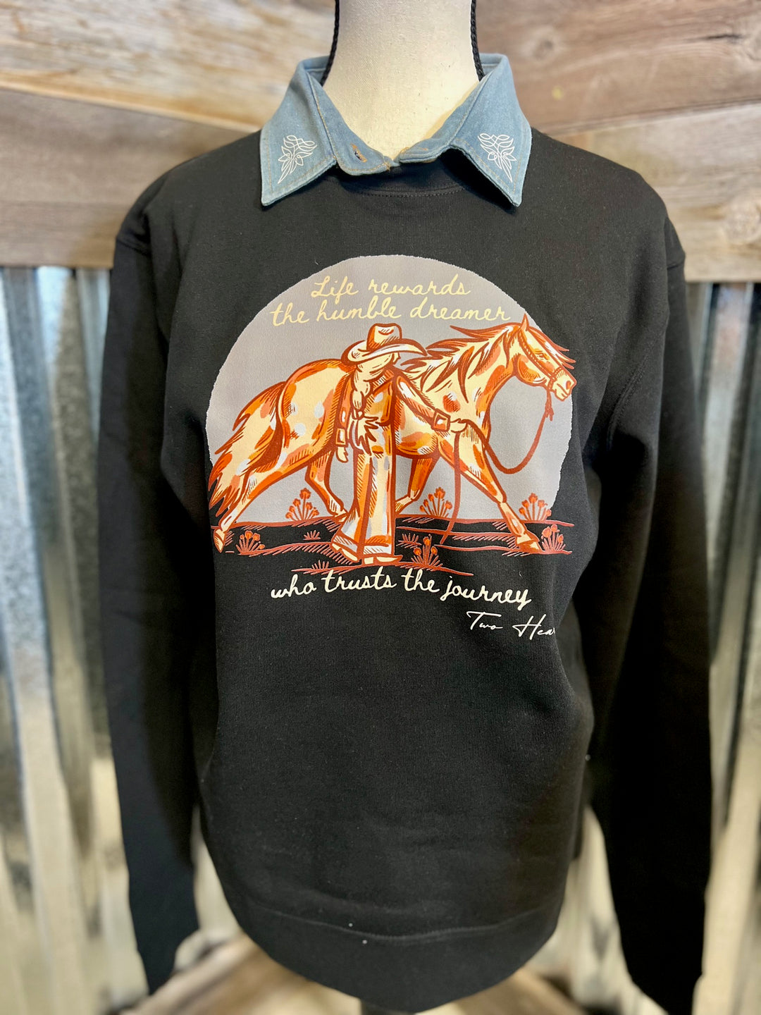 Black sweatshirt with a horse and rider graphic on a mannequin against a wooden background