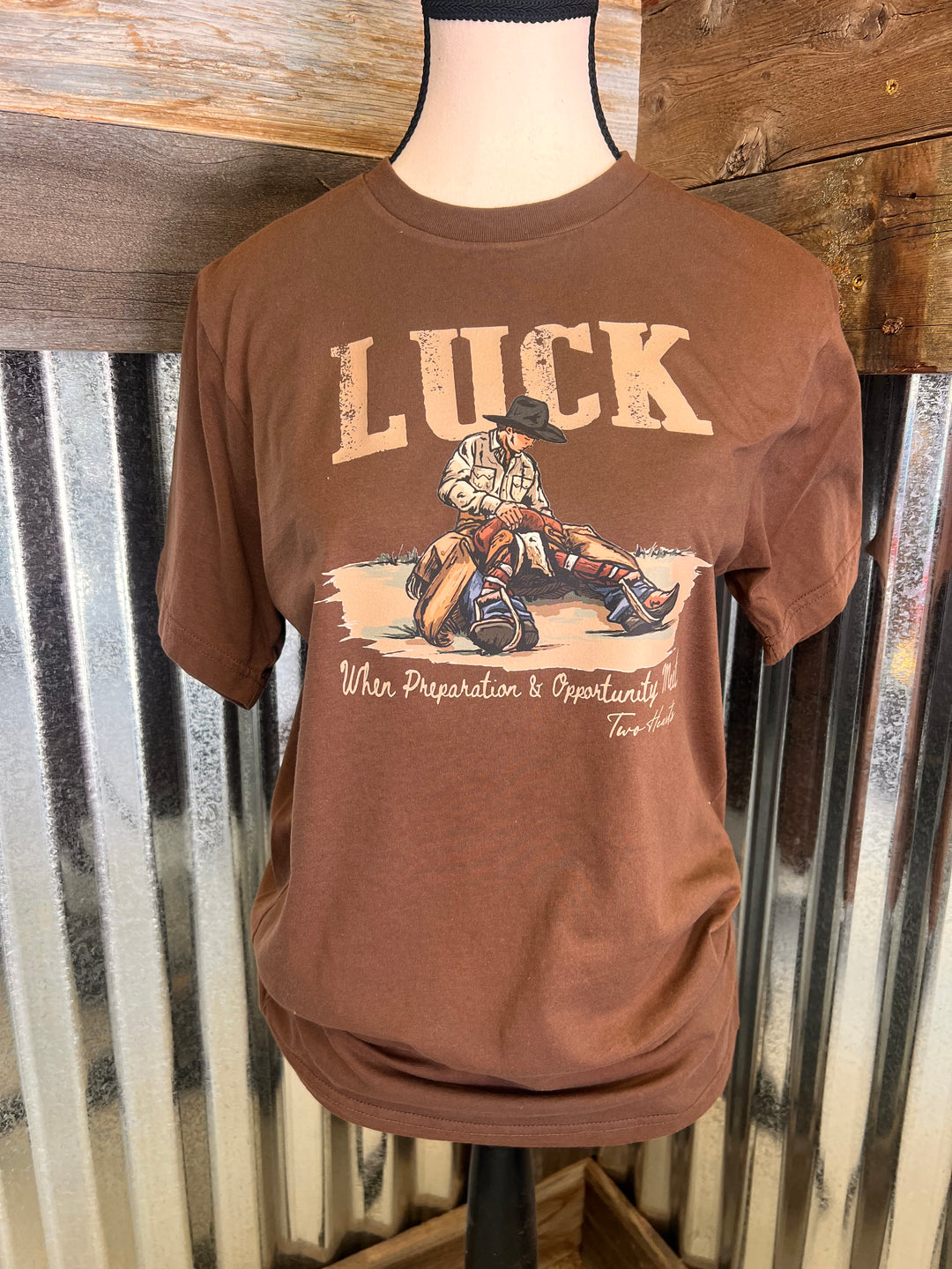 Brown t-shirt with graphic design and text on a metal surface