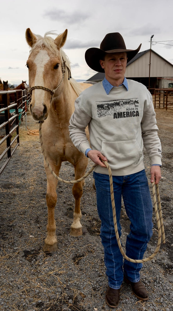 Man in cowboy hat leading a horse in an outdoor setting