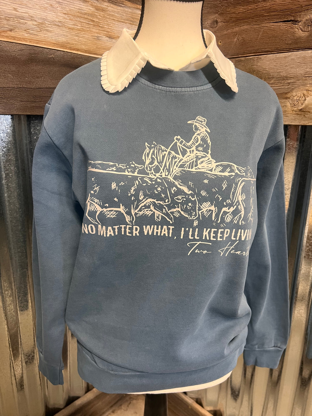 blue sweatshirt with printed design and text on a wooden surface