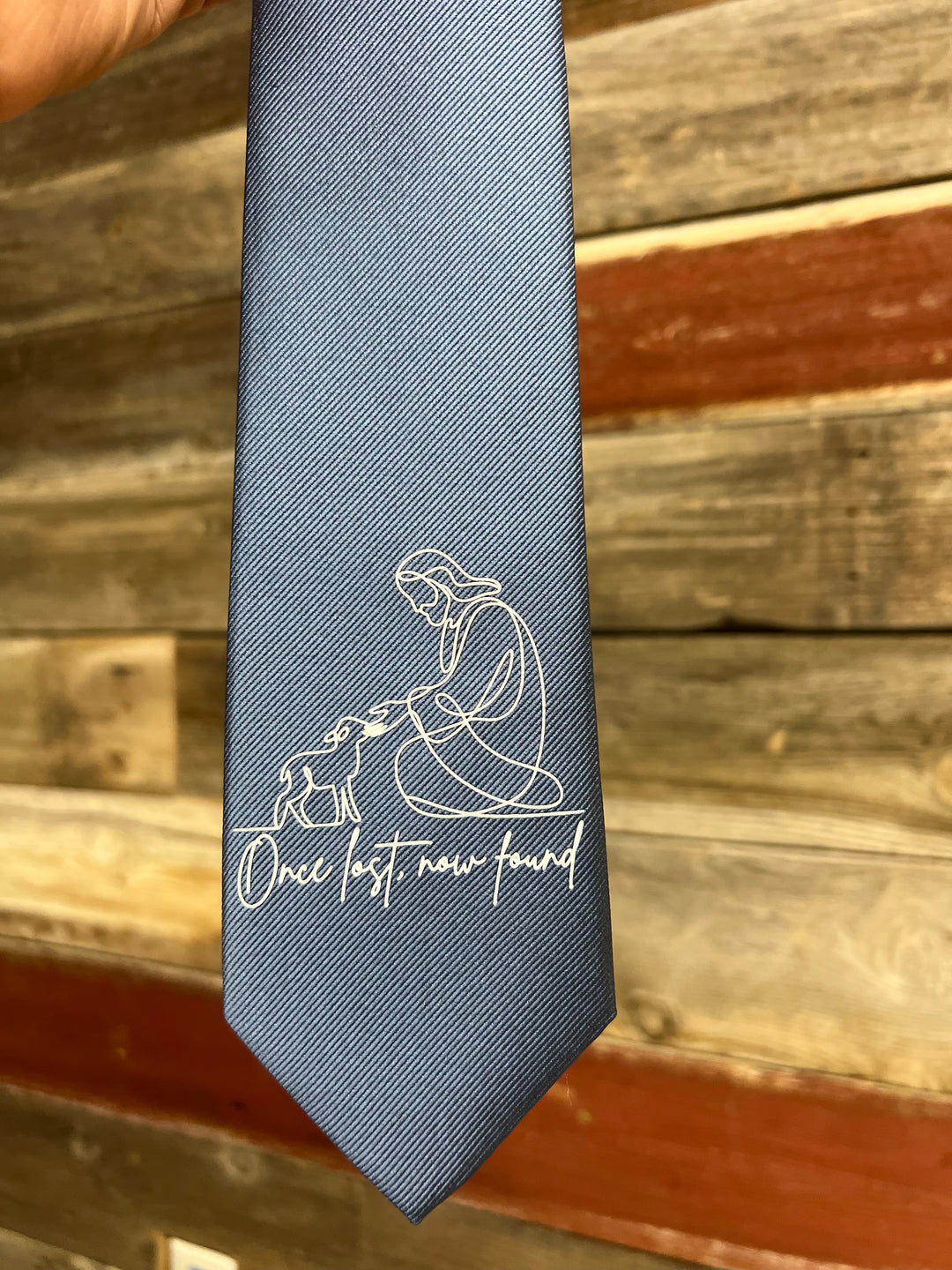 Gray tie with white text and design against a wooden background