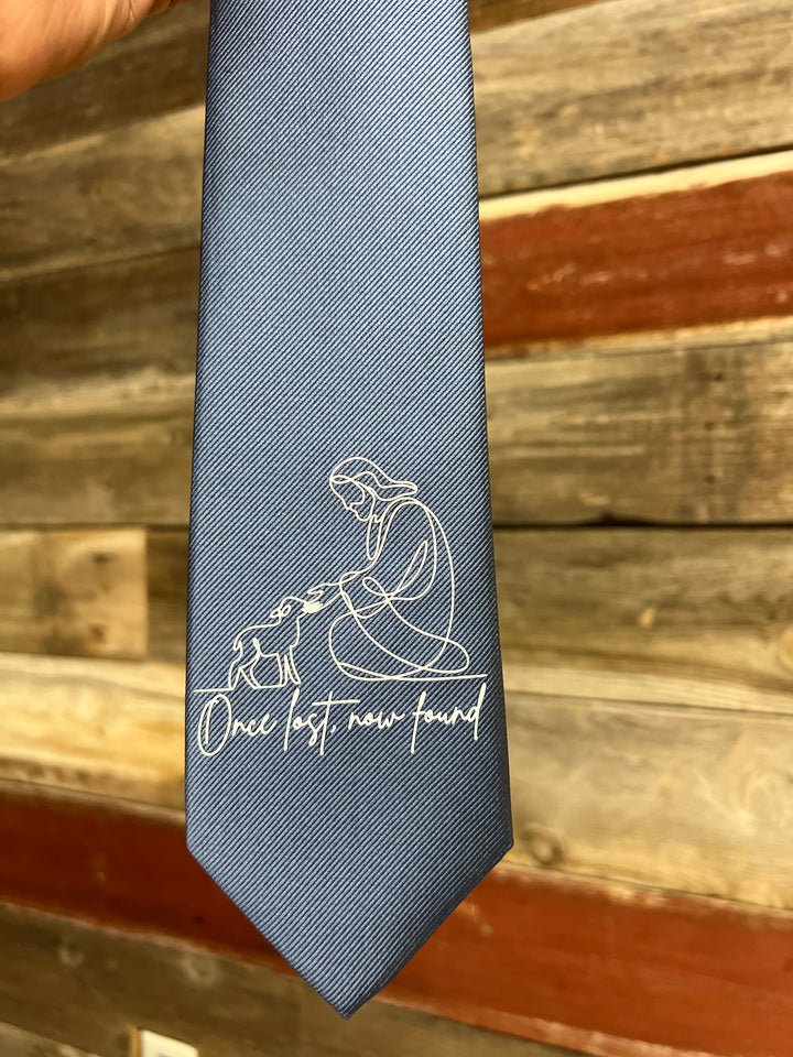 Gray tie with white text and design against a wooden background