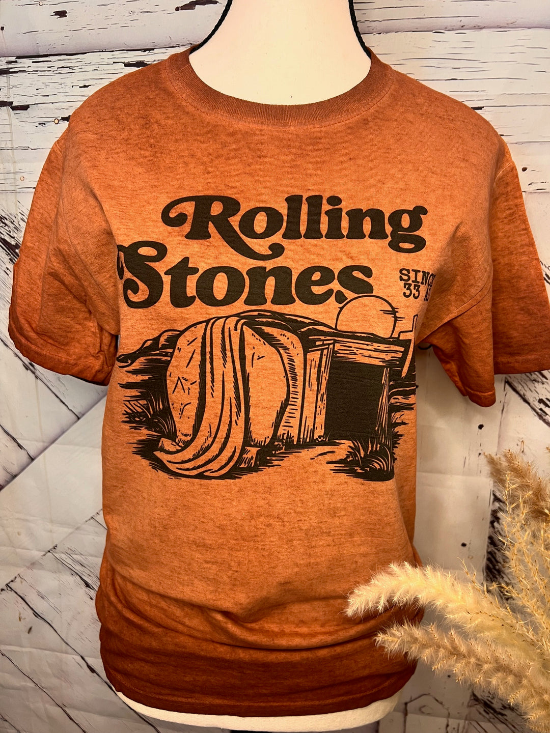 A brown t-shirt with the Rolling Stones band logo replaced with a graphic of a tomb and the text 'He is Risen'.