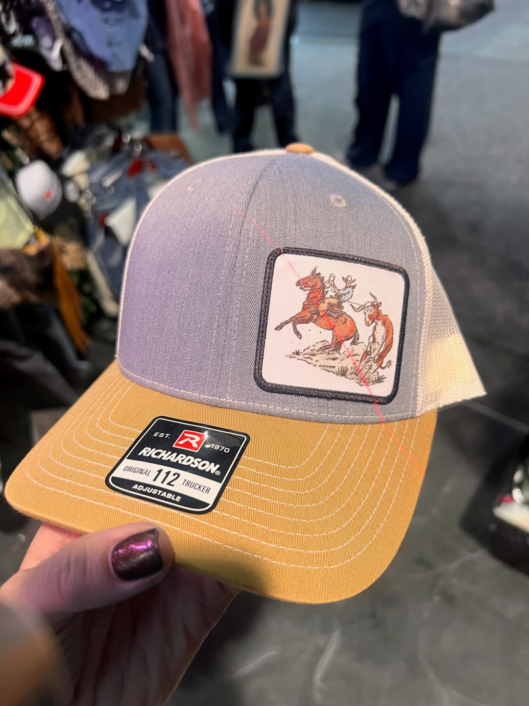 Two baseball caps with logos held up against a blurred background