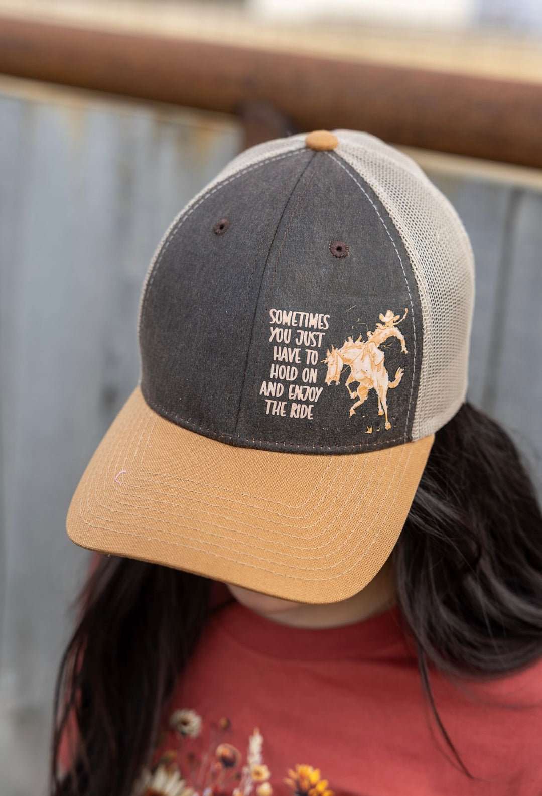 Person wearing a cap with text and a horse graphic, blurred background