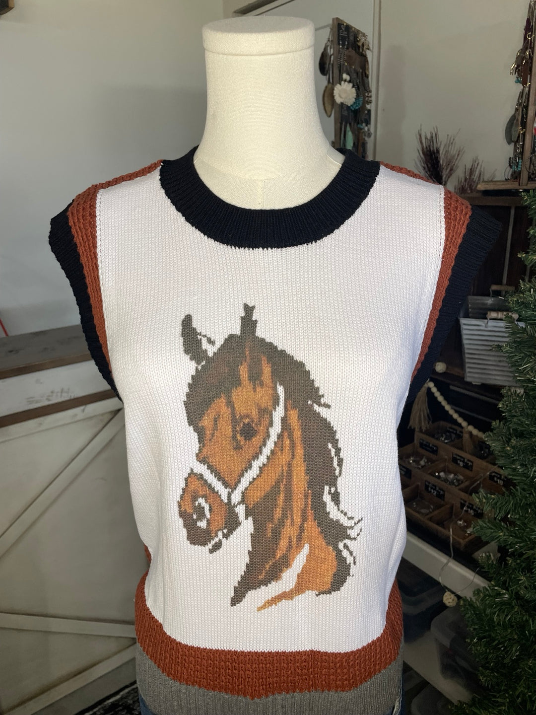 A sleeveless knit sweater displayed on a mannequin torso, featuring a large brown horse head graphic on a white background with dark navy and rust-orange trim.