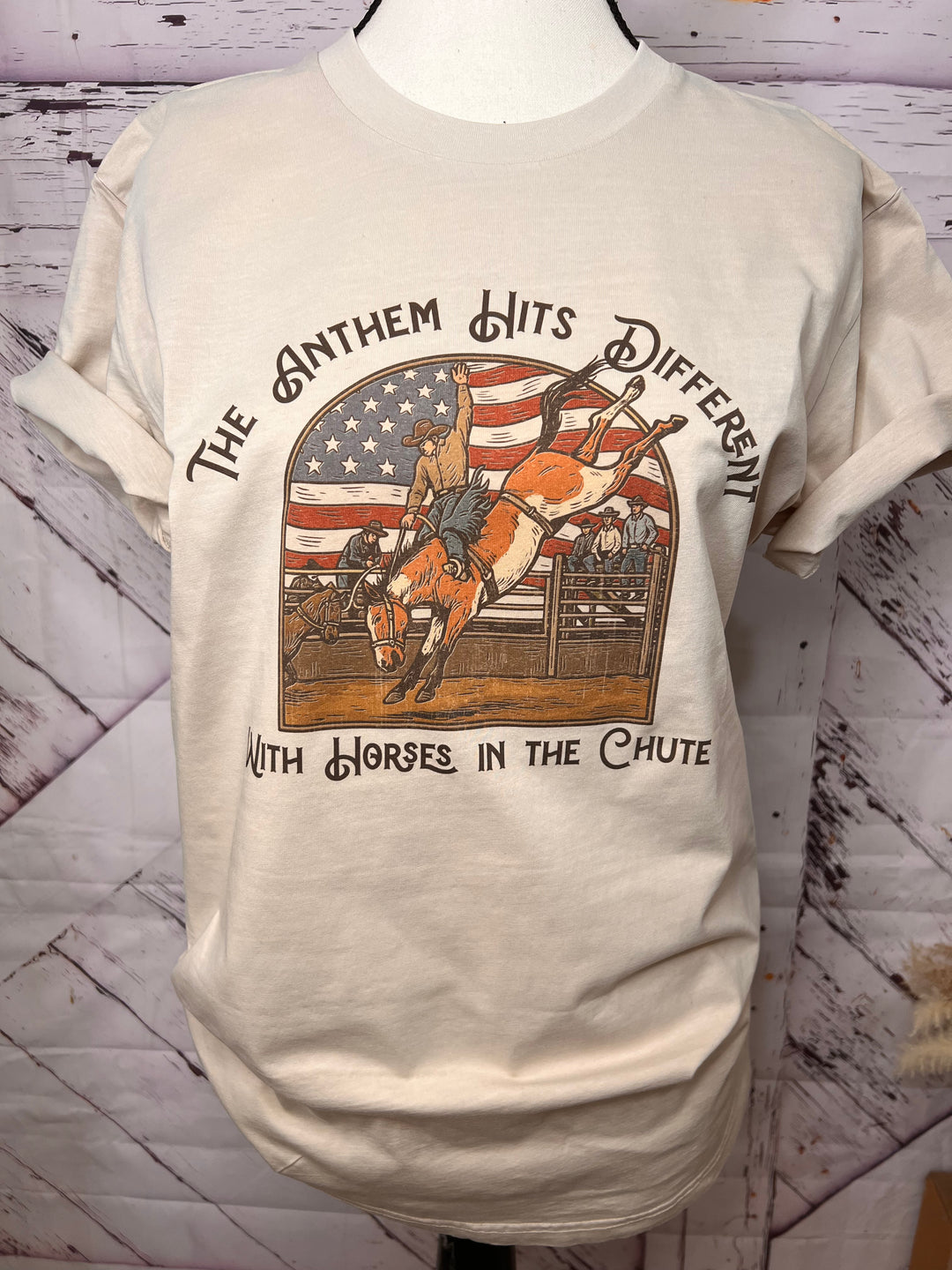 Beige t-shirt with graphic design of a horse and American flag on a wooden surface