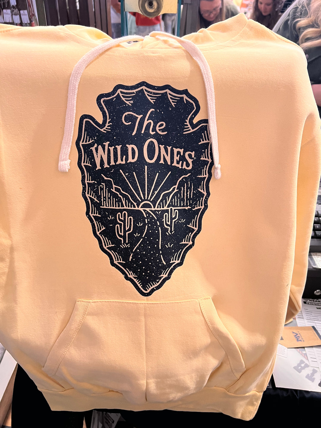 Beige hoodie with a black graphic design on a blurred background