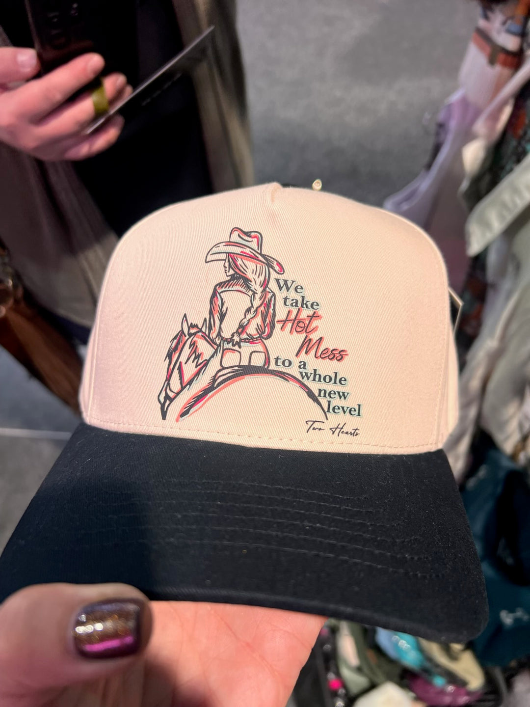 Beige pouch with text and graphic design held by a person in a store setting