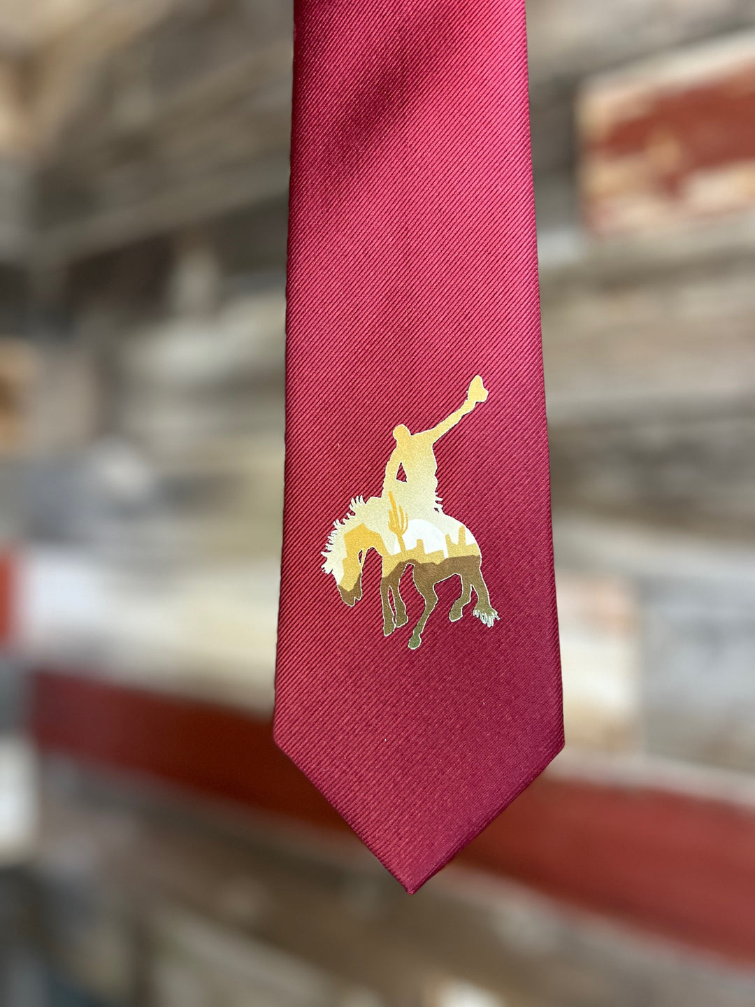 Red tie with a gold emblem of a horse on a blurred background