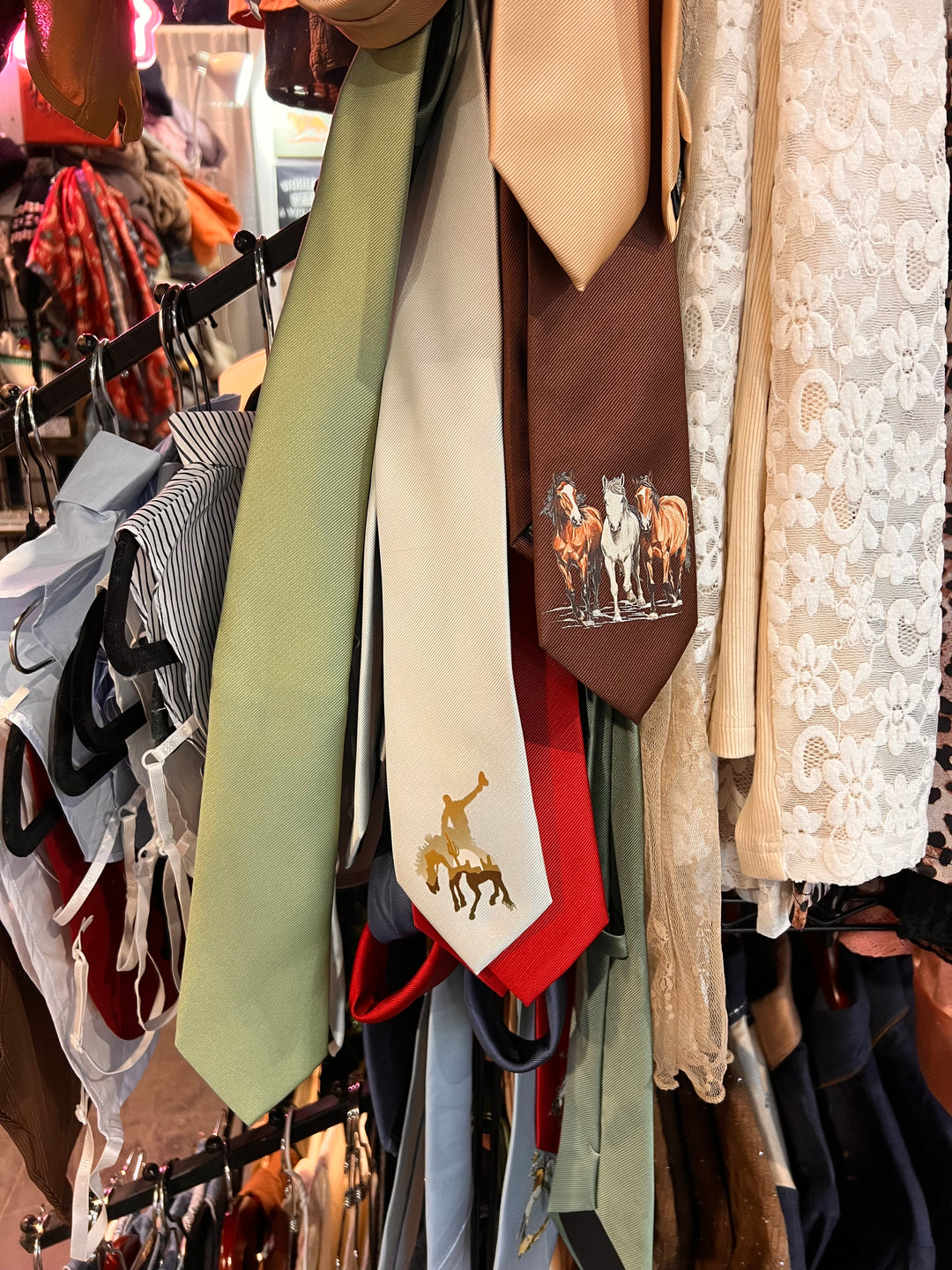 Collection of ties on a rack with various patterns and colors.