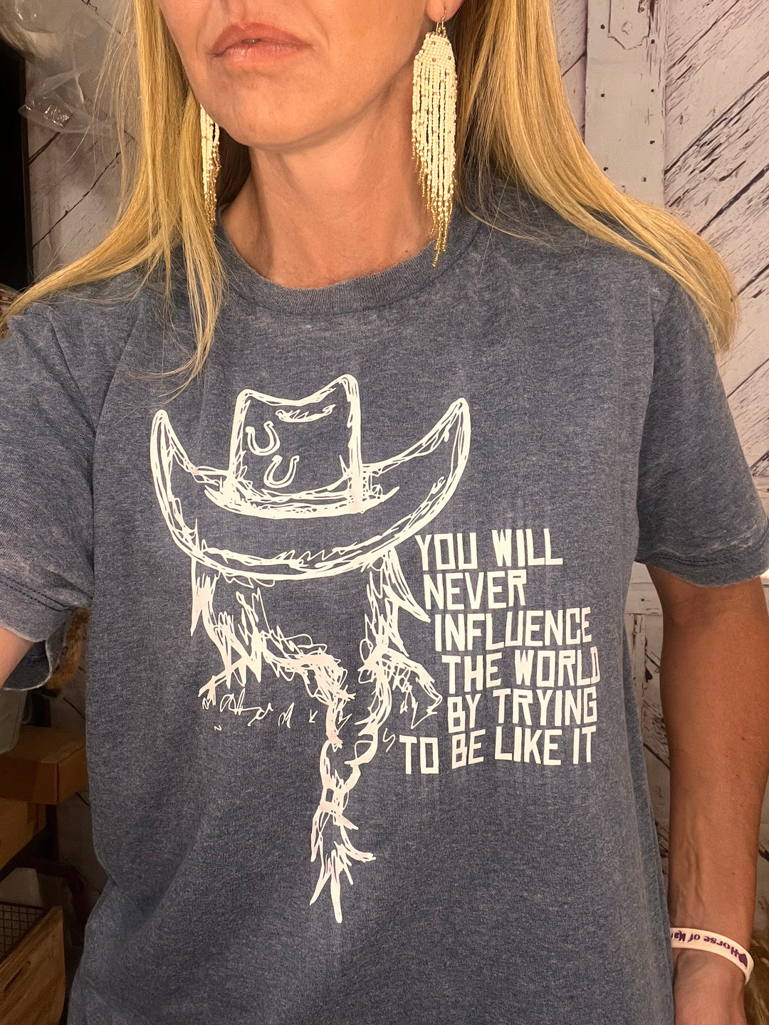 Person wearing a gray t-shirt with a graphic design and text.