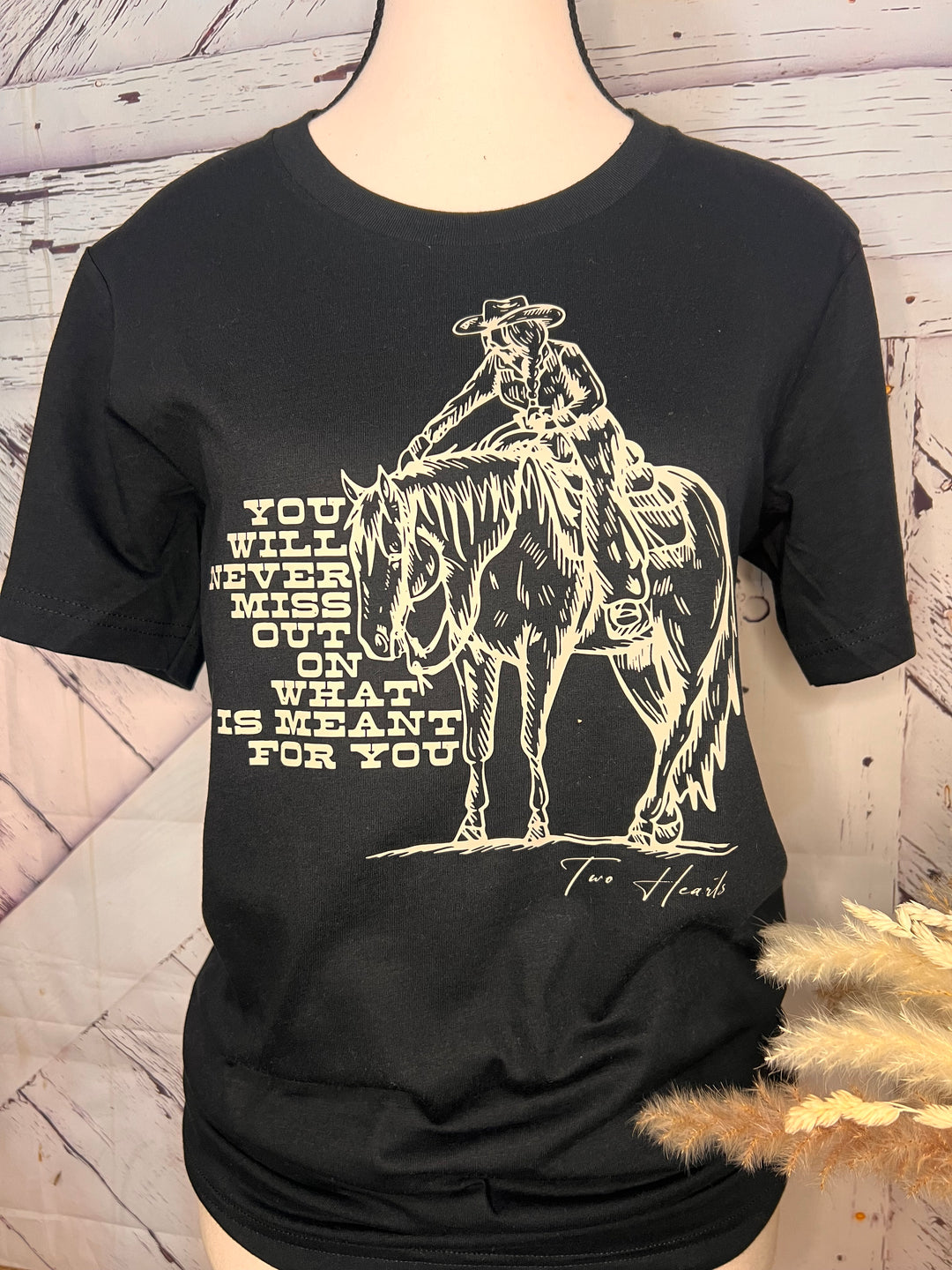 Black long-sleeve shirt with graphic design and text on a wooden surface