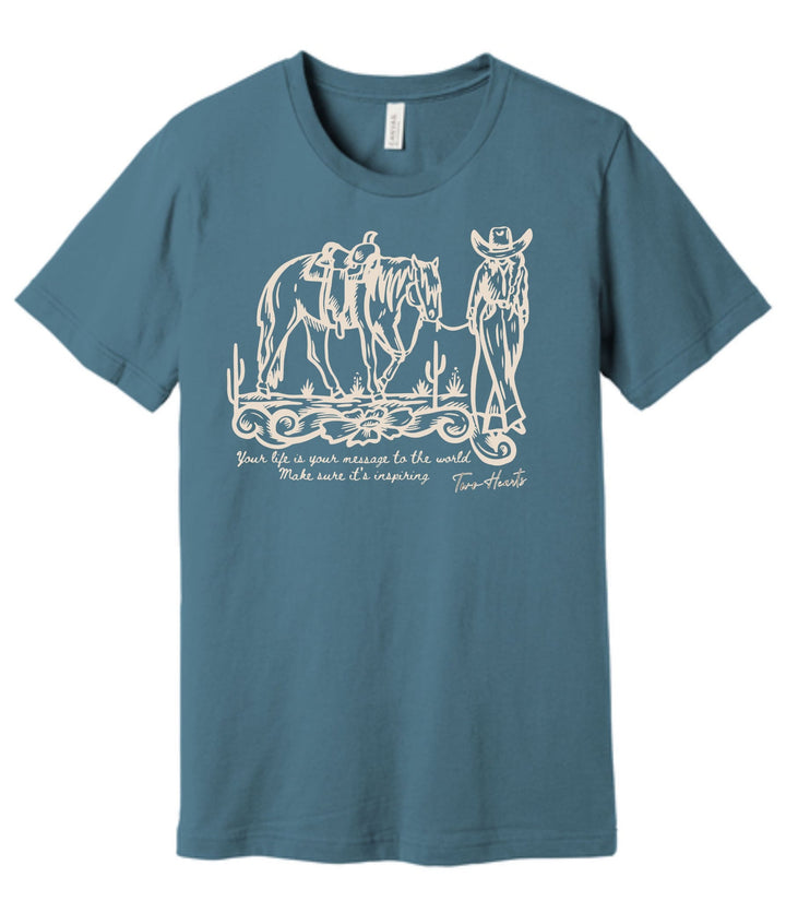 Blue t-shirt with white graphic of a cowboy and horses on a white background