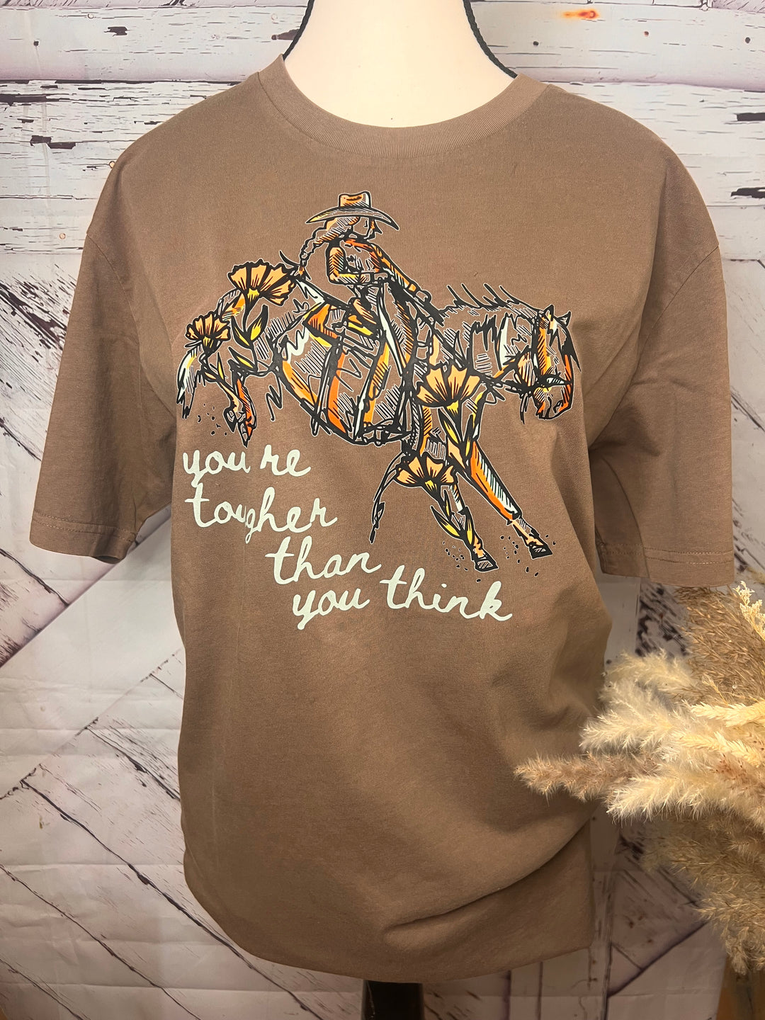 Brown shirt with a graphic design and text on a wooden surface