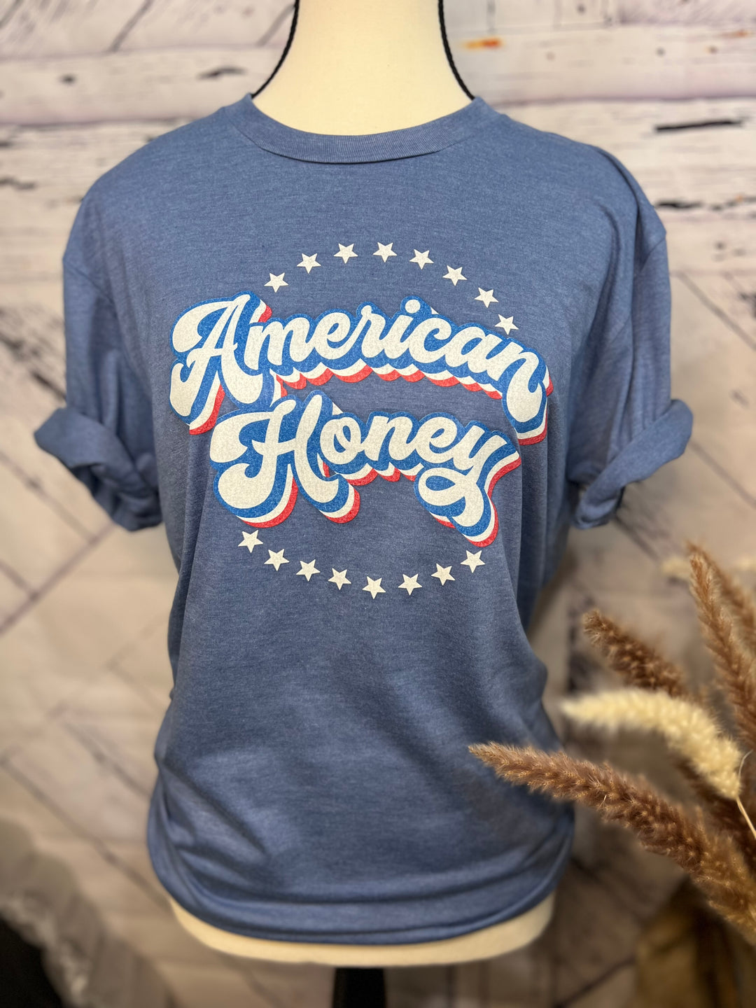 A gray graphic tee with 'American Honey' text in red, white, and blue colors on the front.