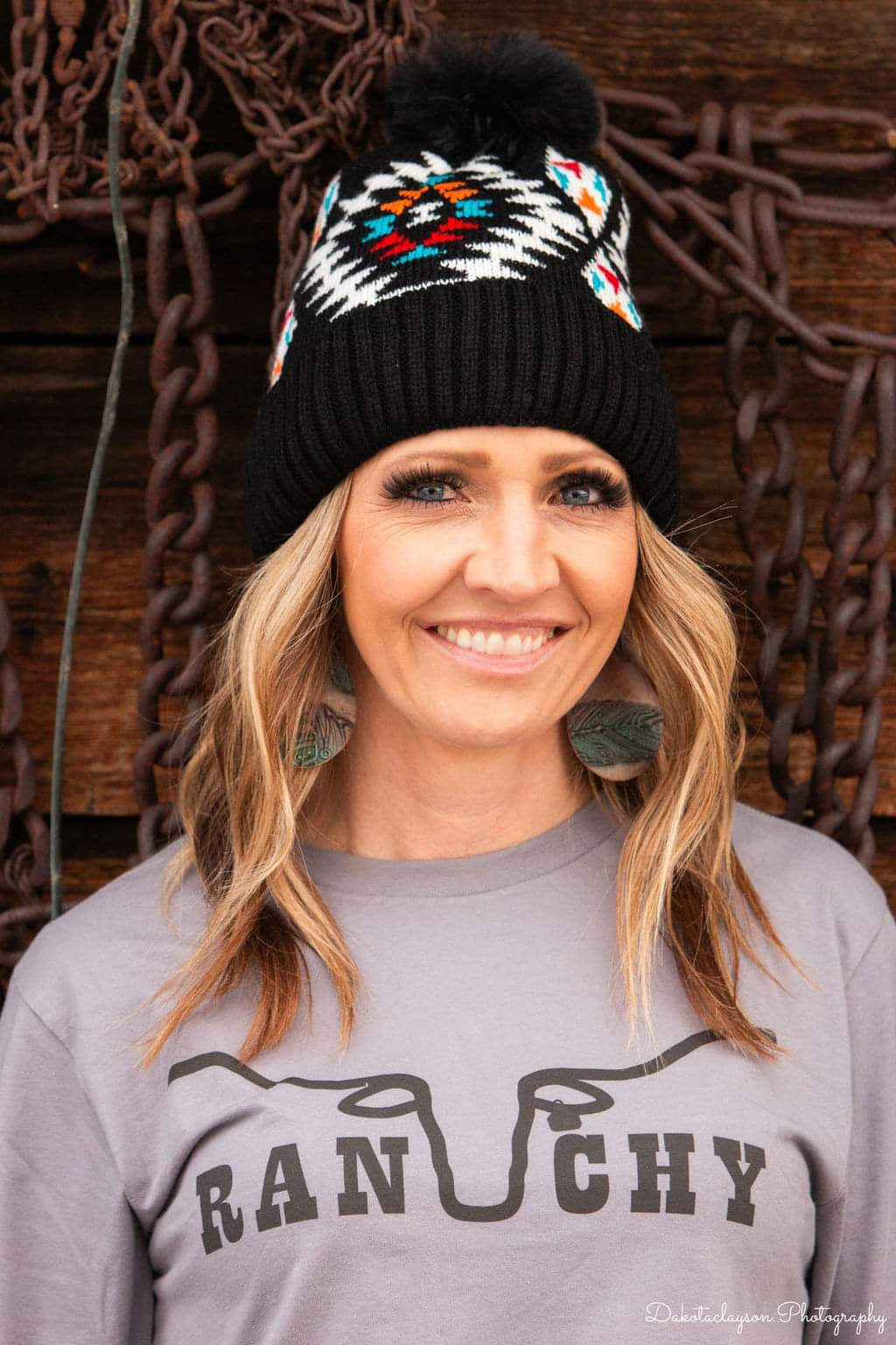 A woman wearing a black beanie with a colorful geometric pattern on the cuff.