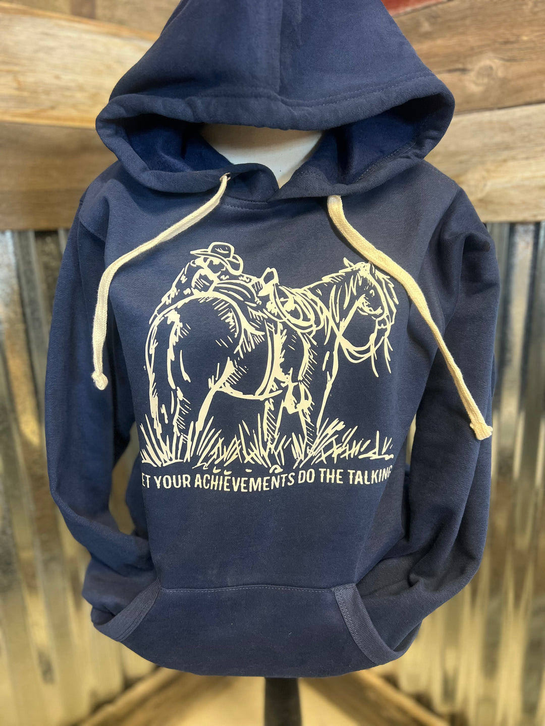 Navy blue hoodie with horse graphic and text on a wooden background