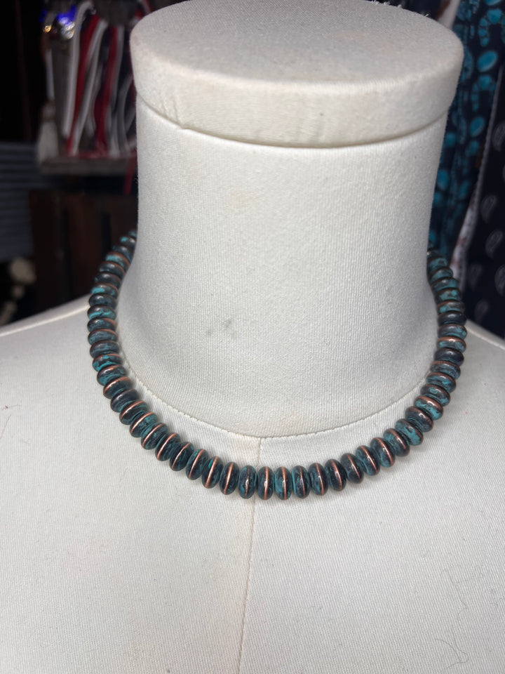 A coiled black cord or strap displayed around a white fabric mannequin bust, with a blurred indoor background.