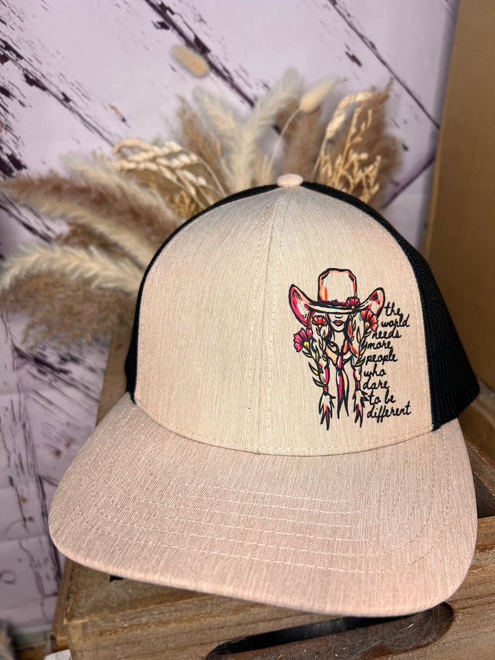 A beige and black trucker cap with a design of a cowgirl and the text &