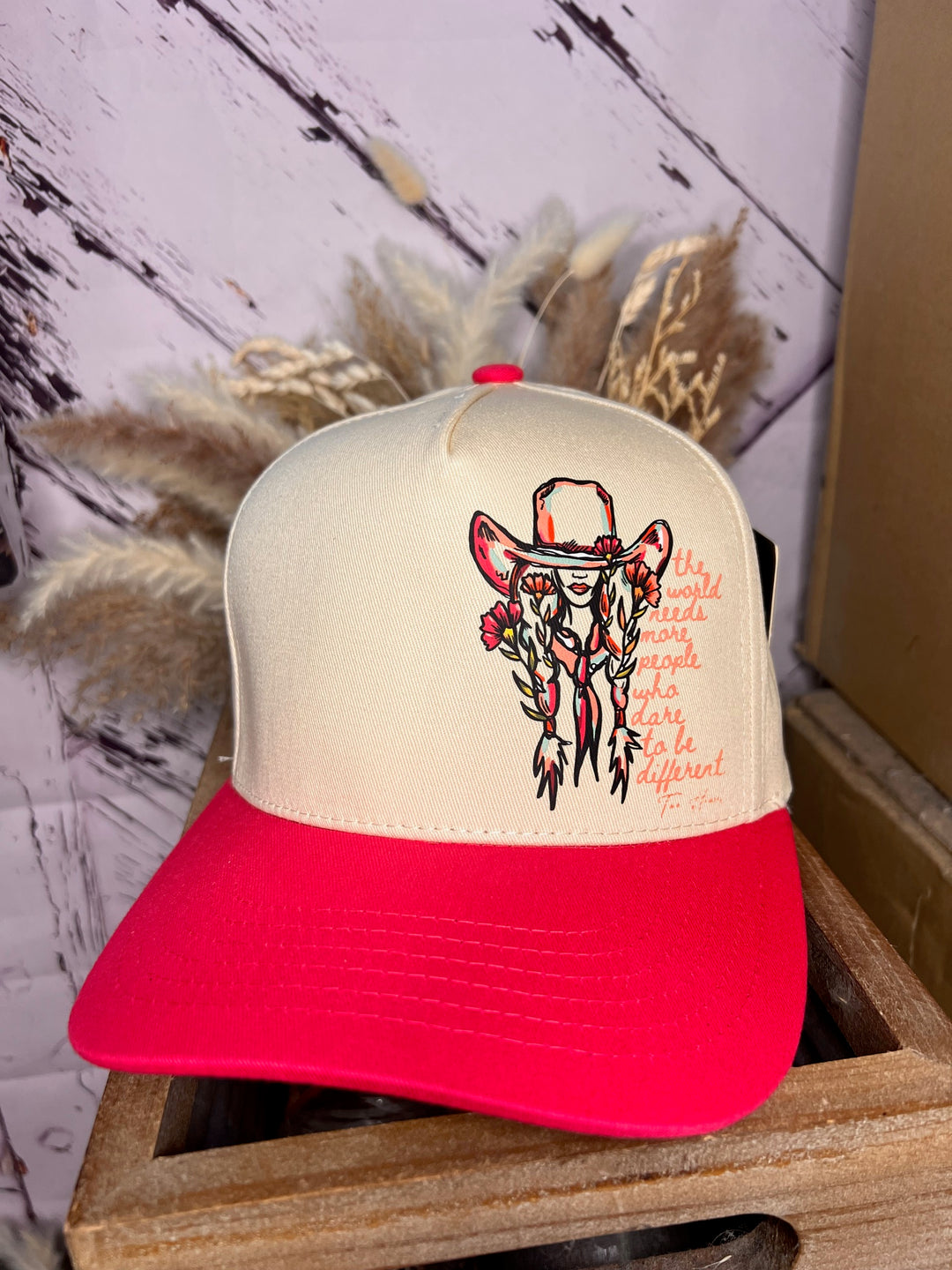 A beige and black trucker cap with a design of a cowgirl and the text &
