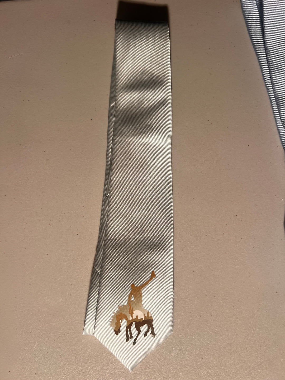 Silver tie with a small design on a beige surface