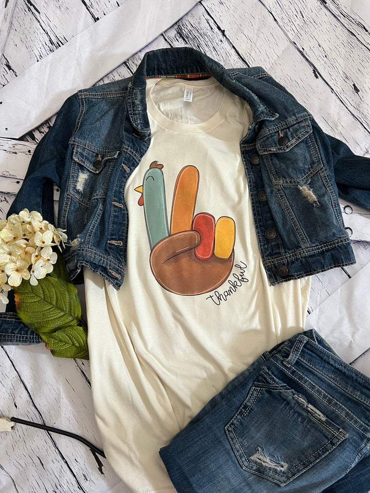 A white crewneck t-shirt with a colorful turkey design and the text &